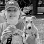 A person holding a ribbon in one hand and a dog in the other.