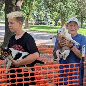 Two people holding dogs in the racing catch pen