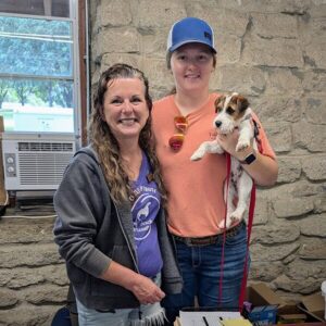 Two women standing together one is holding a dog.